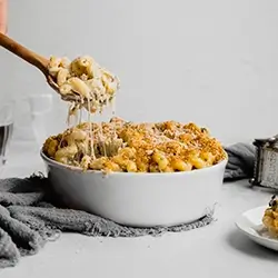 A spoon dipping into a creamy dish of macaroni and cheese.